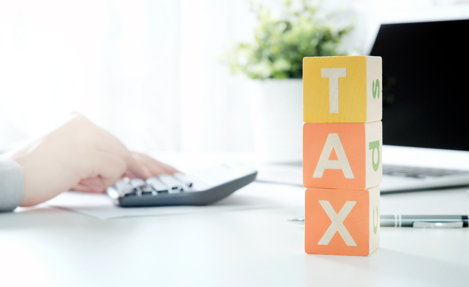 Фотографія рука на калькуляторі, кубики з написом tax