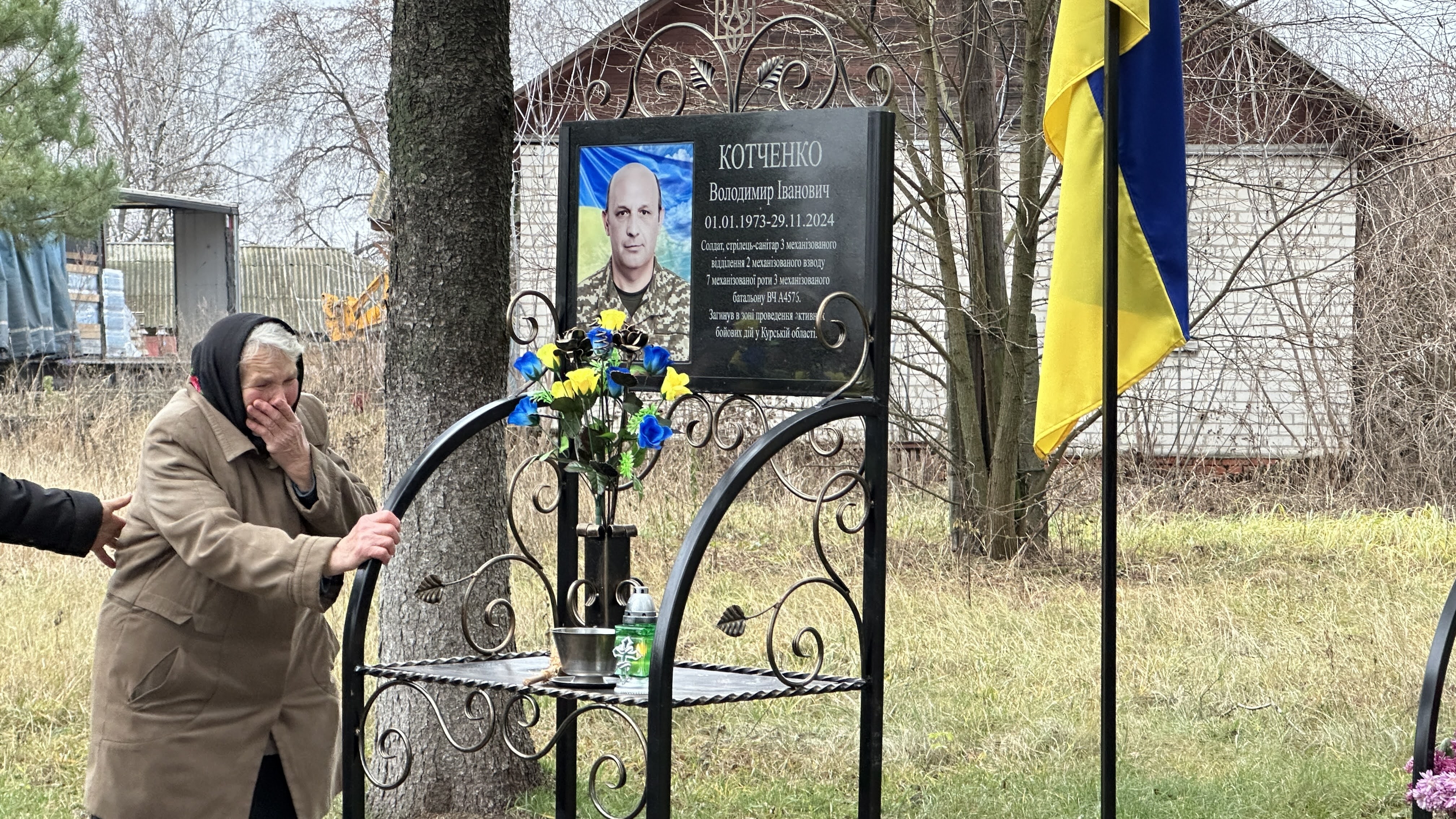Фотографія Мама загблого Героя біля меморіальної дошки