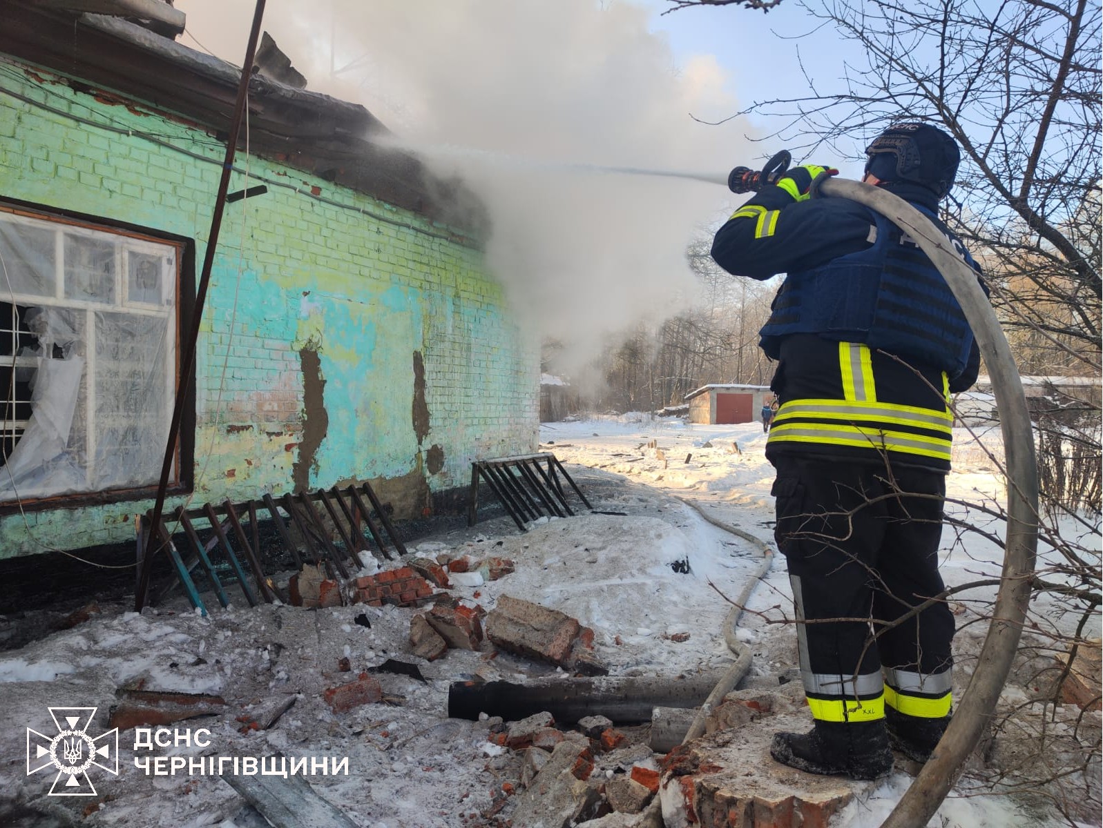 Фотографія взимку рятувальник гасить пожежу в будинку